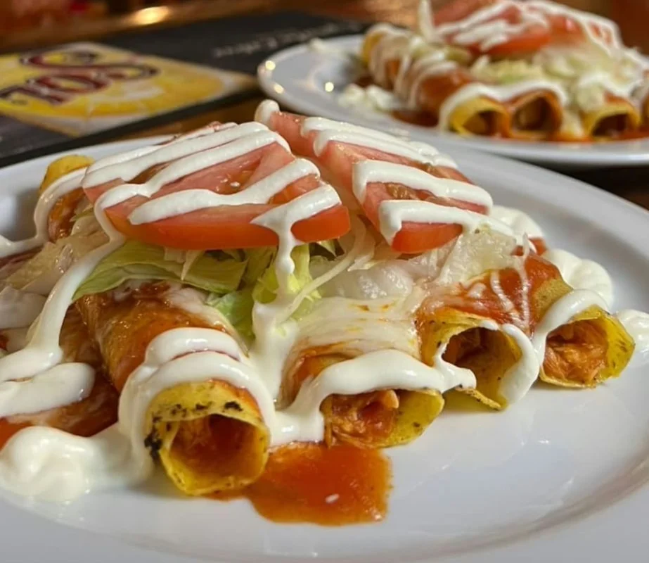 Enchiladas con salsa roja, queso fundido, lechuga, tomate y salsa agria