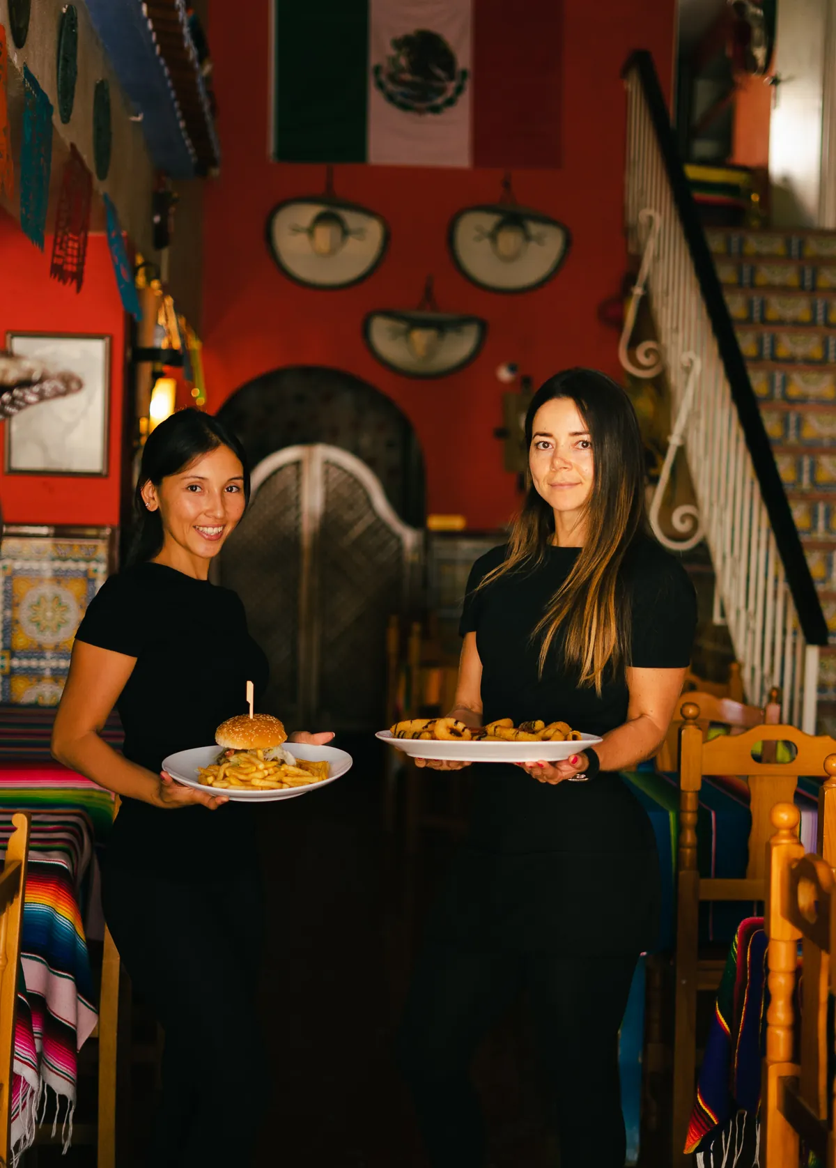 Dos camareras del restaurante sirviendo una hamburguesa y fajitas