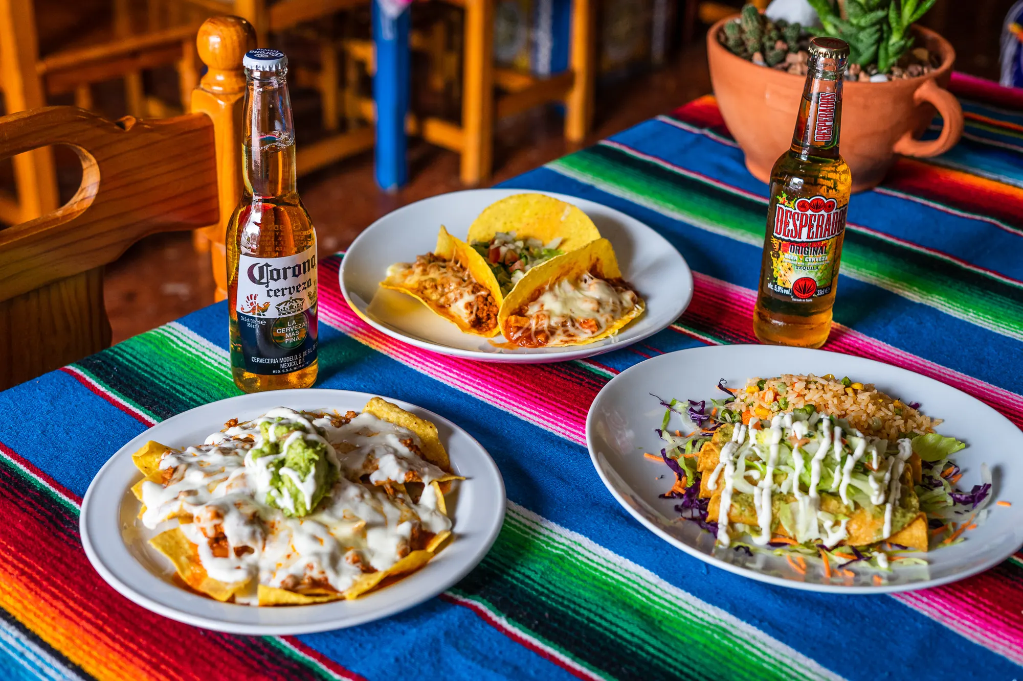 Mesa con nachos, tacos, enchiladas y cervezas